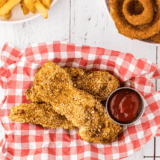 Plate of golden, crispy Arthur Treacher’s style fried chicken with dipping sauce.