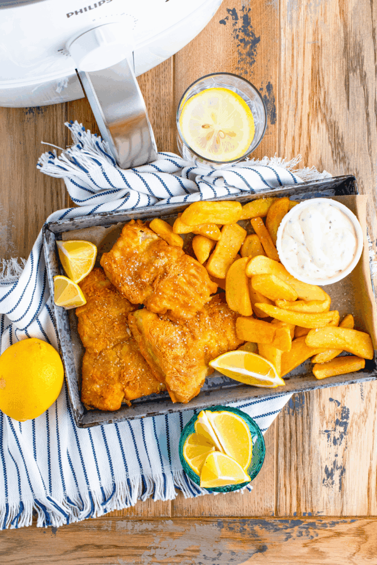 Plate of crispy Arthur Treacher’s style fish and chips served with tartar sauce and lemon wedges.