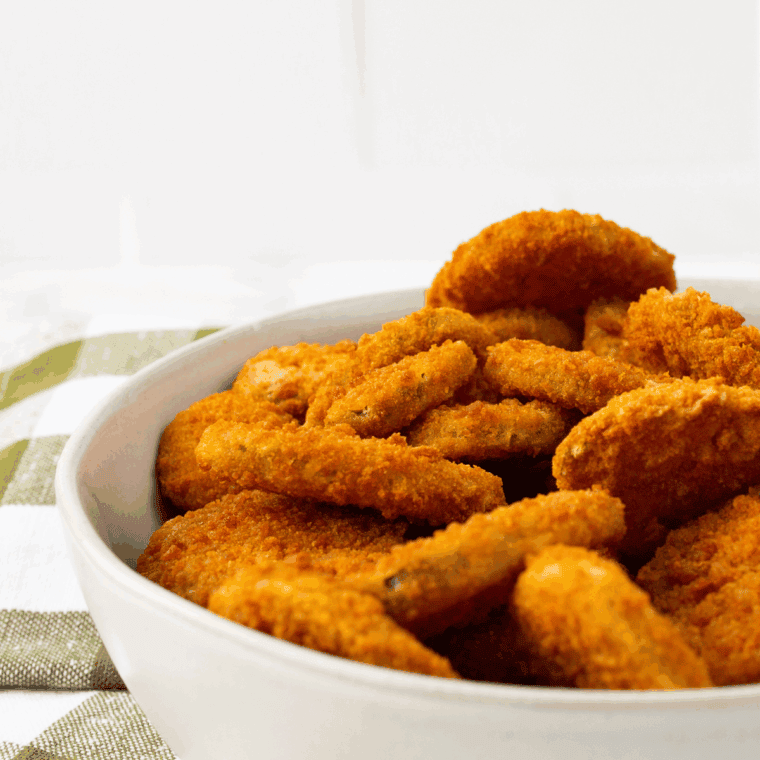 Golden, crispy Arthur Treacher’s fried pickles served with creamy dipping sauce on a white plate.