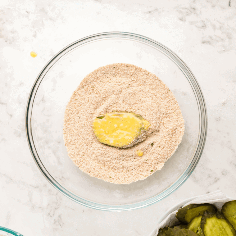 Pickle slices being coated with crispy panko breadcrumbs before air frying.