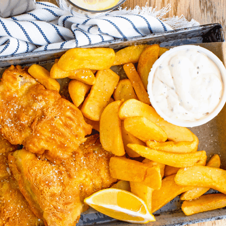 Bowl of homemade Arthur Treacher’s tartar sauce with spoon, served beside crispy fried fish and fries.
