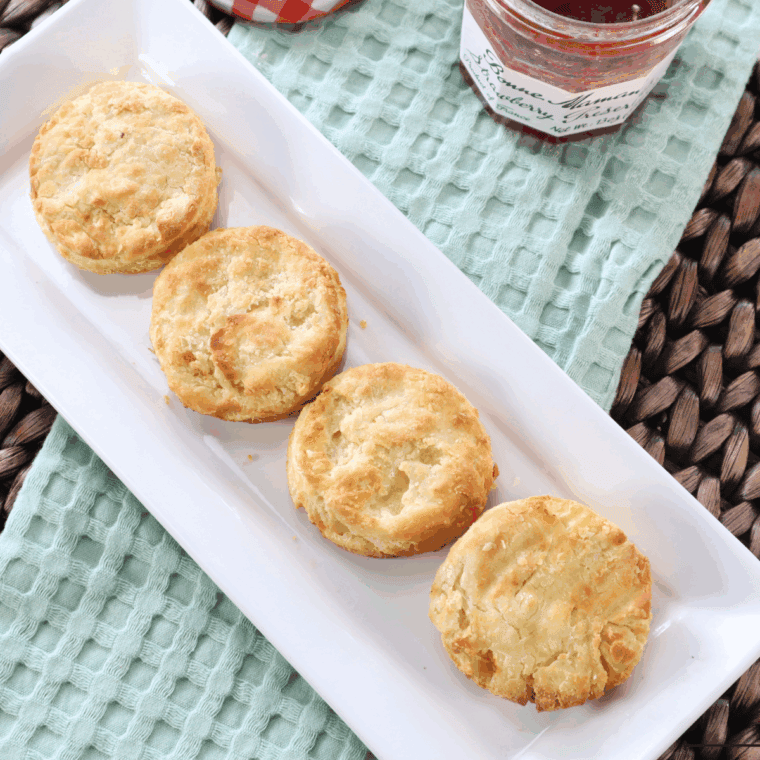 Golden, fluffy Bob Evans style buttermilk biscuits stacked on a white plate, showcasing a flaky texture and buttery crust.