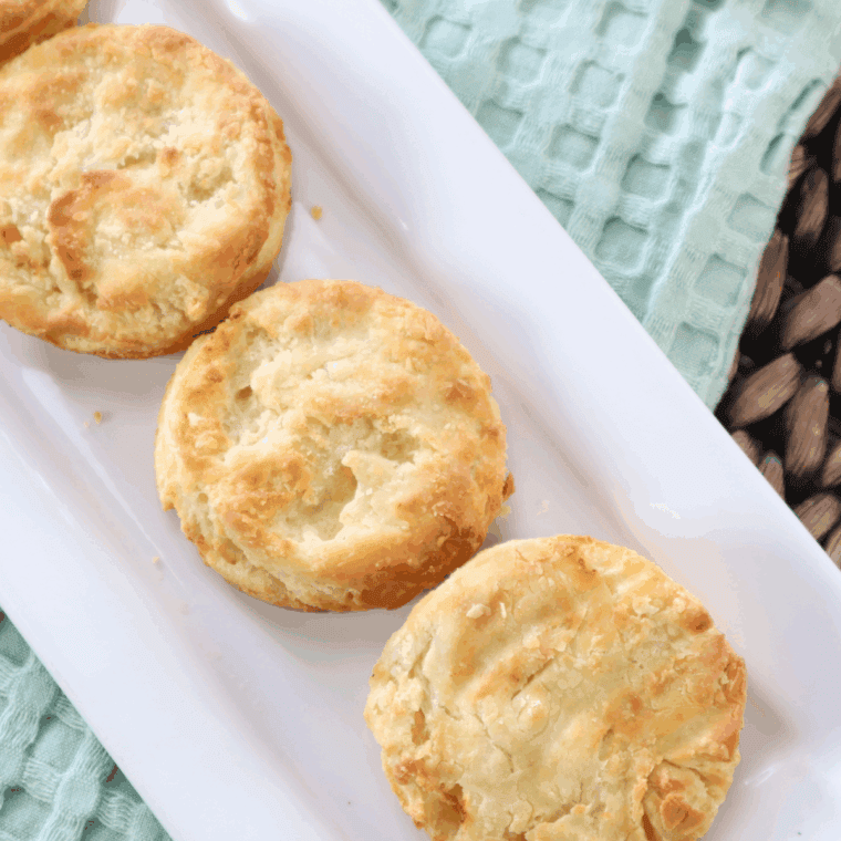 Golden brown Bob Evans style buttermilk biscuits stacked on a plate, showing a flaky, soft texture inside.