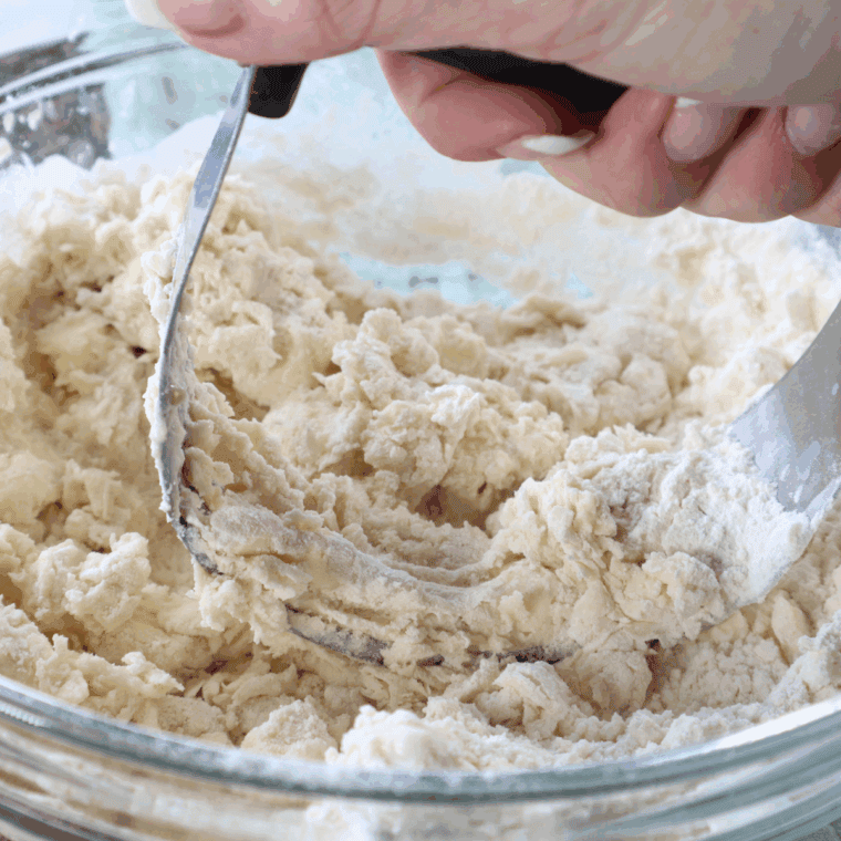 Cutting cold butter into the flour mixture with a pastry cutter to create coarse crumbs, then adding buttermilk and gently stirring.
