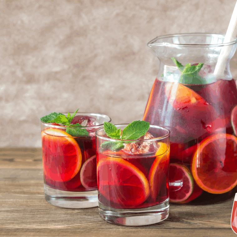 Glass of homemade Red Lobster-style sangria with fresh citrus slices and berries on a wooden table.