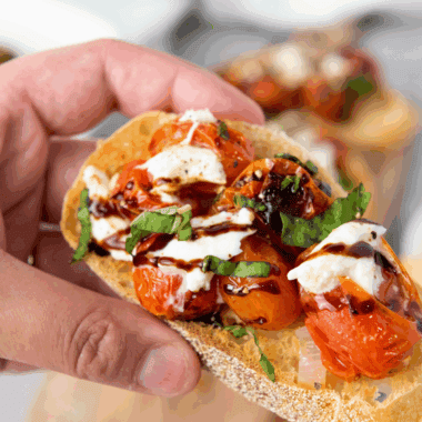 Plated Carrabba’s Tomato Caprese with creamy burrata, sliced tomatoes, fresh basil, and balsamic glaze drizzle.