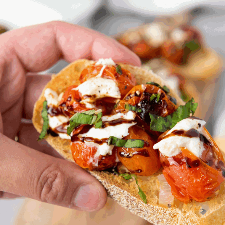 Plated Carrabba’s Tomato Caprese with creamy burrata, sliced tomatoes, fresh basil, and balsamic glaze drizzle.