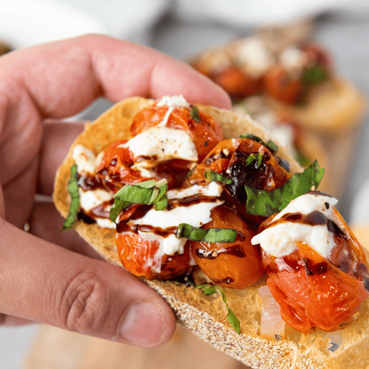 Plated Carrabba’s Tomato Caprese with creamy burrata, sliced tomatoes, fresh basil, and balsamic glaze drizzle.