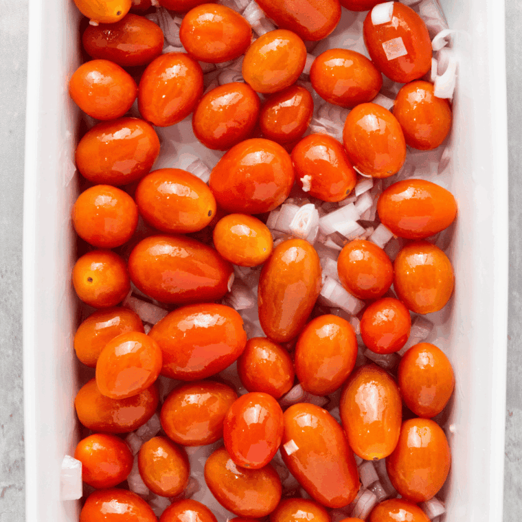 Cherry tomatoes, shallots, garlic, and olive oil in a baking dish.