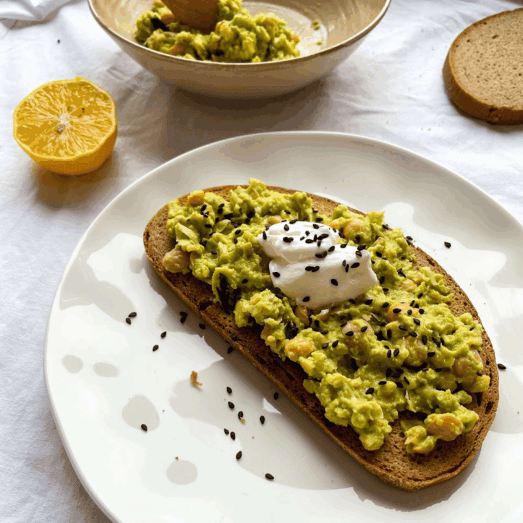 Cheesecake Factory-style avocado toast topped with cherry tomatoes and microgreens on toasted sourdough bread.