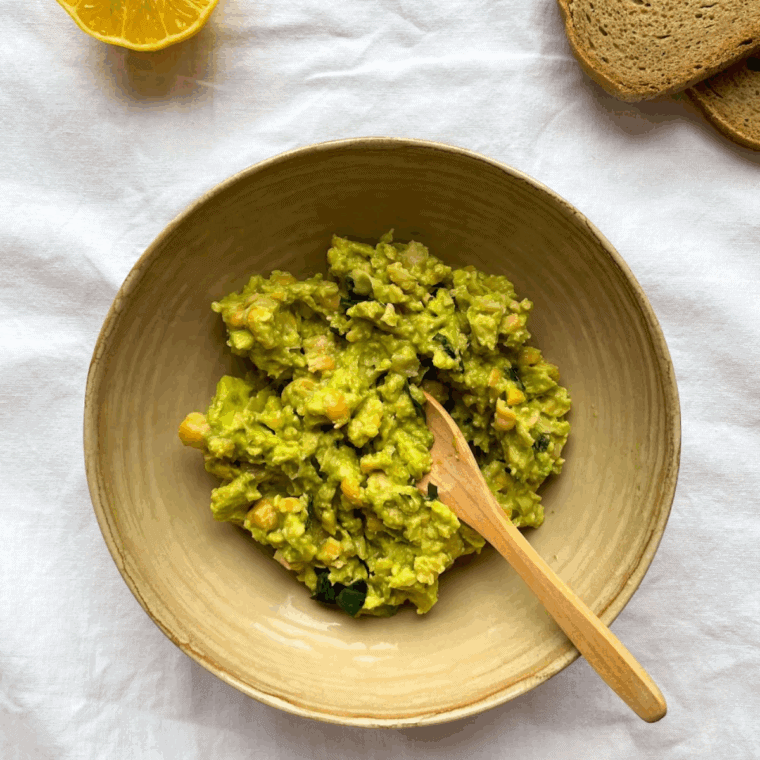 Mashed avocado in a small bowl with lemon juice, salt, and pepper, slightly chunky in texture.