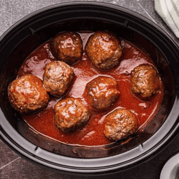 Crockpot filled with simmering meatballs cooking slowly in rich marinara sauce.