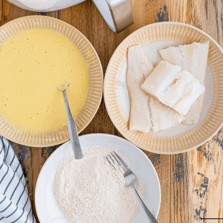 Fish fillets being dredged in flour, dipped in batter, then coated with panko breadcrumbs for a crispy crust.
