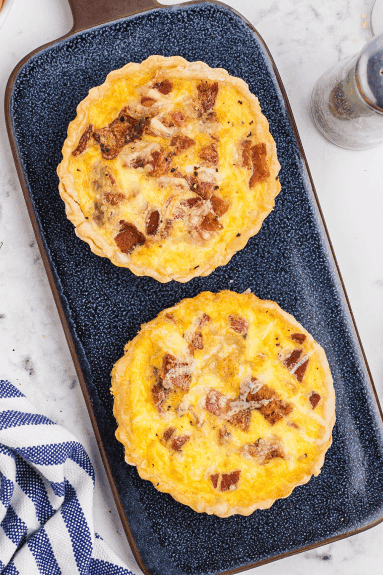Slice of homemade bacon and cheddar quiche on a plate, golden crust and melted cheese visible, inspired by Cracker Barrel’s signature breakfast.
