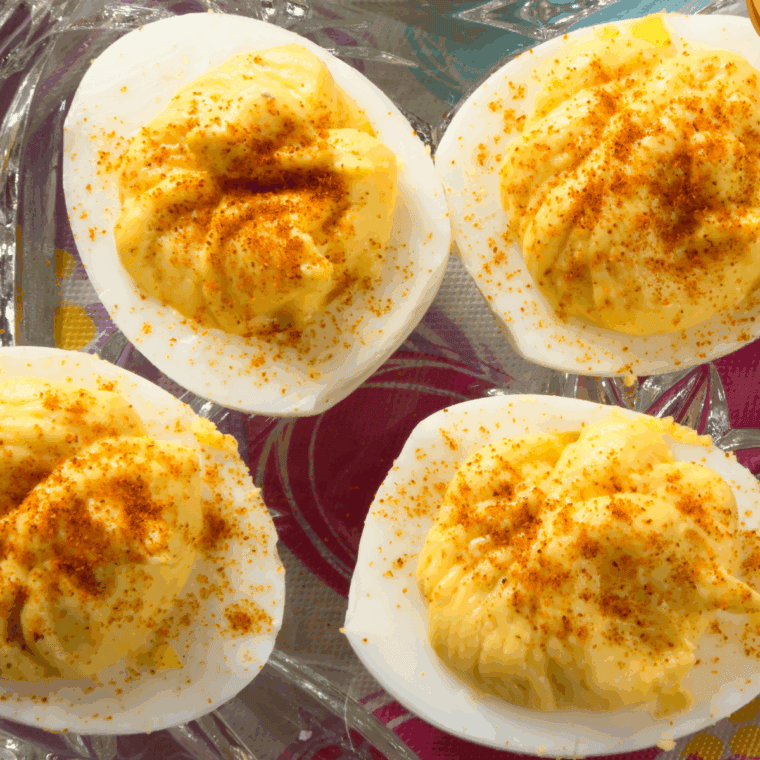 Creamy deviled duck eggs garnished with smoked paprika and fresh herbs on a serving platter.