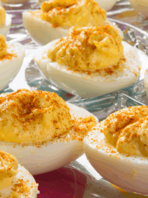 Deviled duck eggs topped with smoked paprika and fresh herbs on a serving platter.