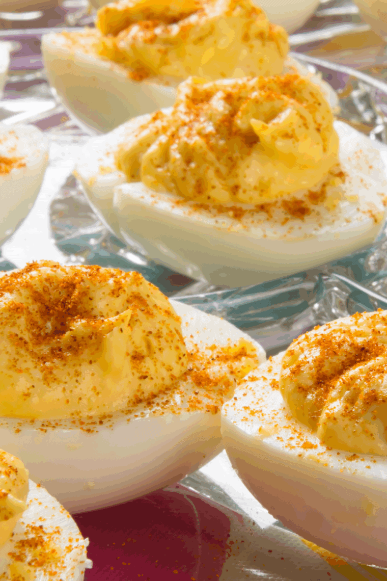 Deviled duck eggs with creamy yolk filling, garnished with smoked paprika and fresh herbs on a platter.