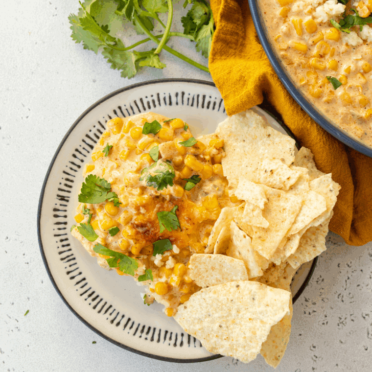 Baked Mexican Street Corn Casserole with melted cheese, chili powder, lime, and fresh cilantro in a serving dish.
