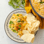 Baked Mexican Street Corn Casserole with melted cheese, chili powder, lime, and fresh cilantro in a serving dish.