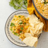 Baked Mexican Street Corn Casserole with melted cheese, chili powder, lime, and fresh cilantro in a serving dish.