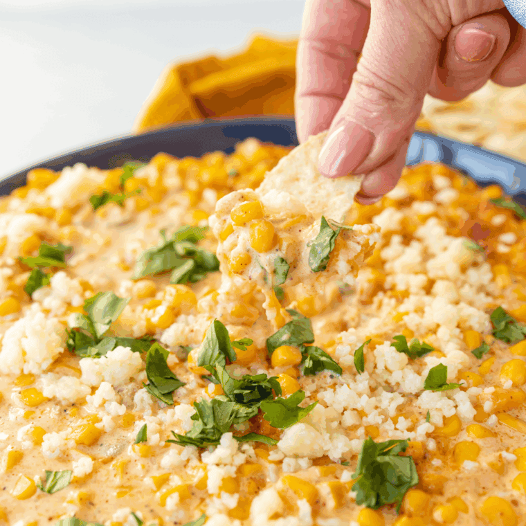 Baked Mexican Street Corn Casserole topped with melted cheese, chili powder, lime, and fresh cilantro in a serving dish.