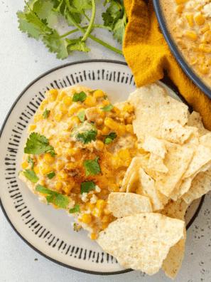 Baked Mexican Street Corn Casserole with melted cheese, chili powder, lime, and fresh cilantro in a serving dish.