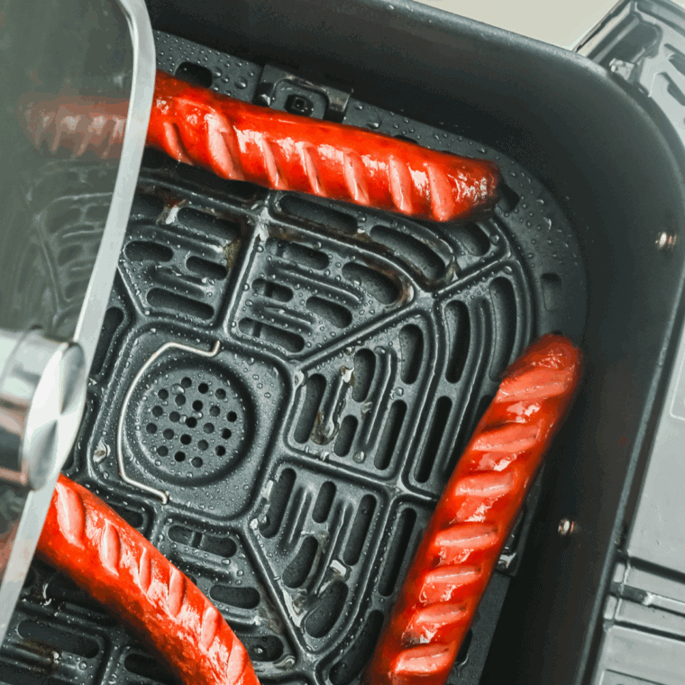 Cooked hot dogs in the air fryer basket.