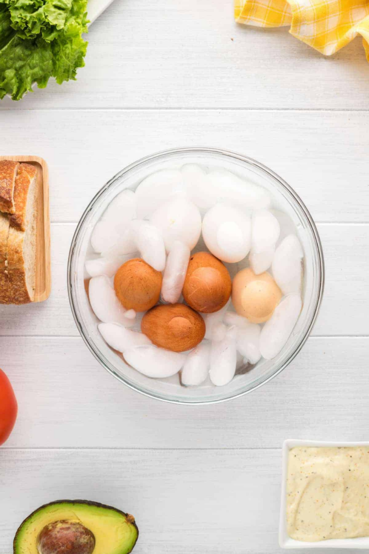 Hard boiled eggs cooling in a bowl of ice water to stop cooking and prevent the gray-green ring around the yolks