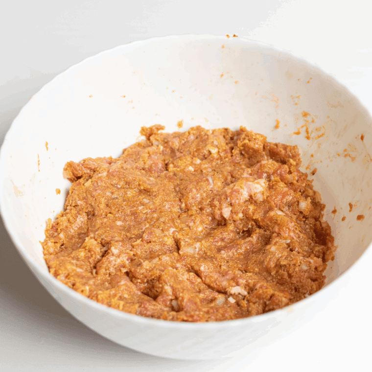 Mixing ground beef, breadcrumbs, milk, onions, and seasonings in a large bowl for meatloaf mixture.