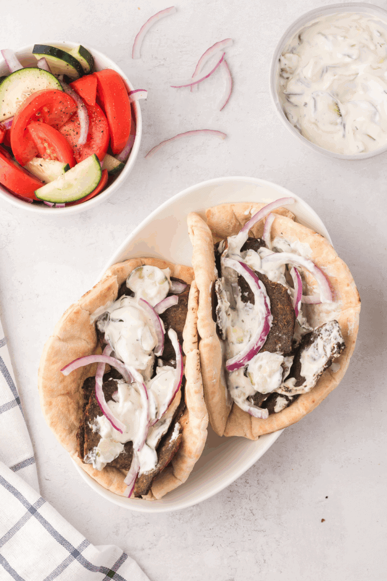Creamy Arby’s Gyro Sauce served in a white bowl with fresh herbs and cucumber slices.