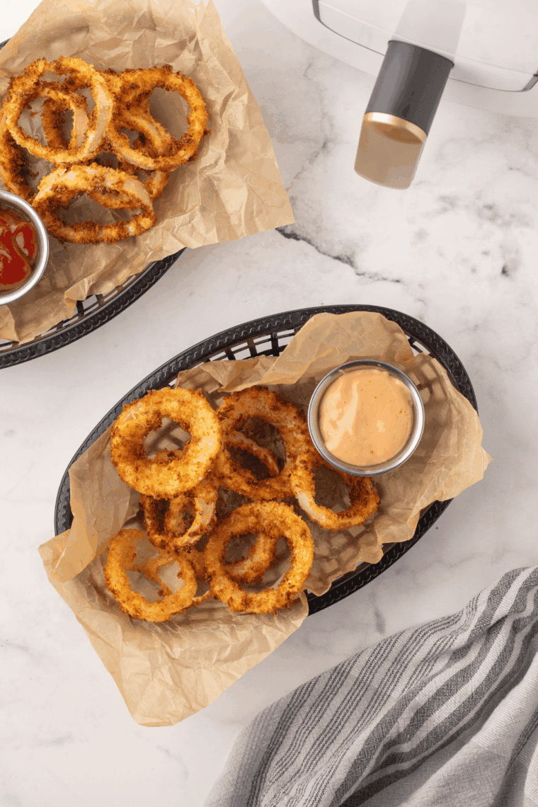 Crispy, golden Hooters-style onion rings stacked on a plate.