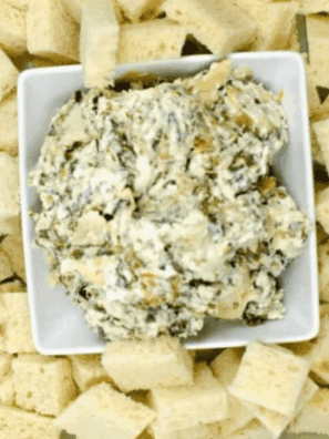 Baked Ina Garten Spinach Artichoke Dip in a white dish, hot and bubbly with golden cheese on top.