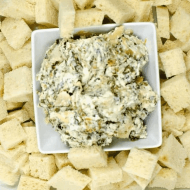 Baked Ina Garten Spinach Artichoke Dip in a white dish, hot and bubbly with golden cheese on top.
