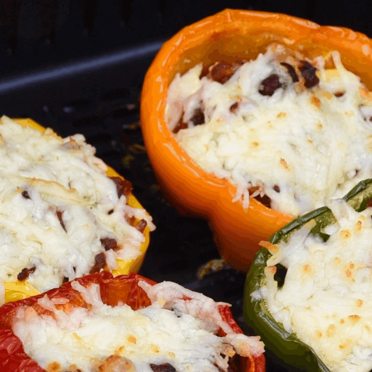 Baked Ina Garten stuffed peppers filled with beef, rice, herbs, and topped with melted cheese in a casserole dish.