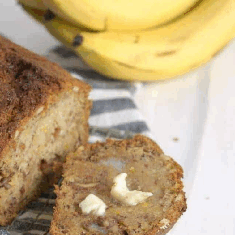Ina Garten’s banana bread loaf on a wooden board, golden brown with a soft, moist texture and slices ready to serve.