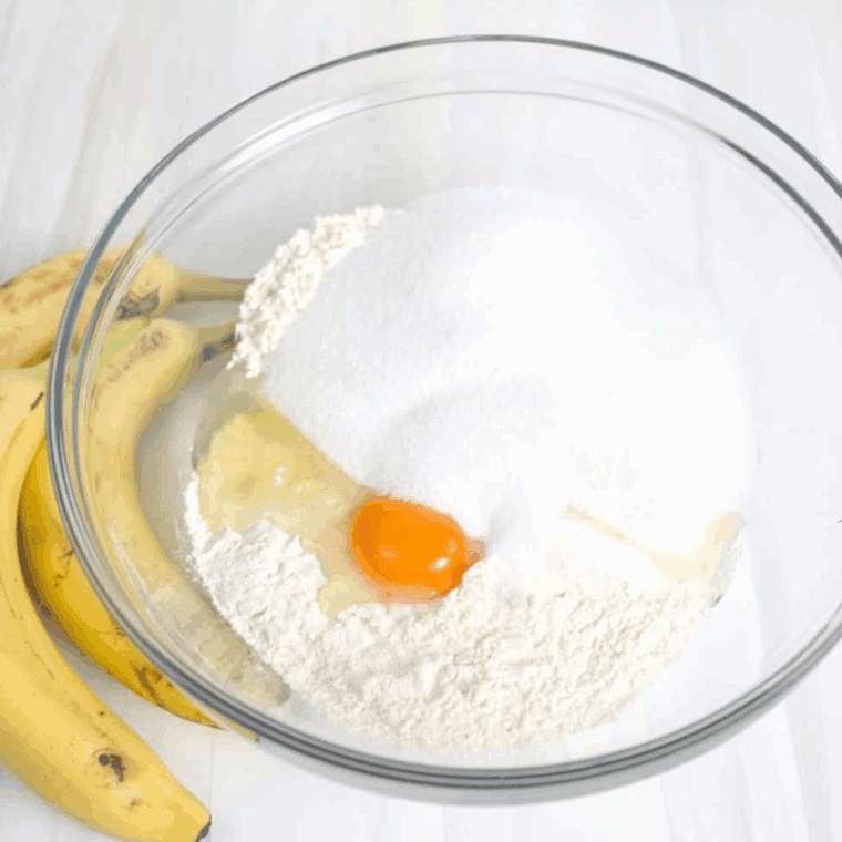 Mixing melted butter, eggs, buttermilk, vanilla, and mashed bananas in a bowl.