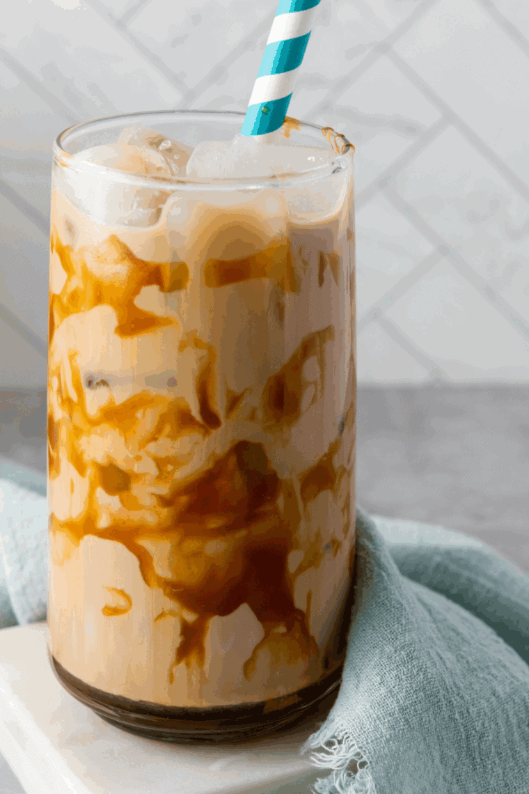 Iced homemade Jack In The Box Creamaccino in a glass topped with whipped cream and caramel drizzle.


