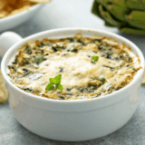 Homemade Longhorn Steakhouse copycat Parmesan Crusted Spinach Dip served in a skillet with golden cheese topping and chips for dipping.