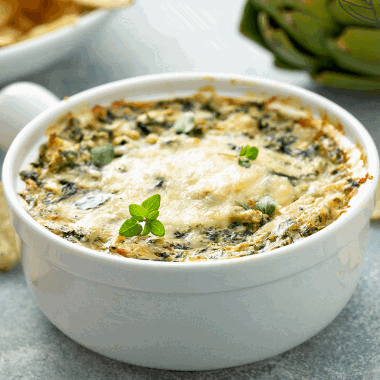 Baked Longhorn Steakhouse style Parmesan crusted spinach dip in a skillet, golden brown on top and served with chips for dipping.