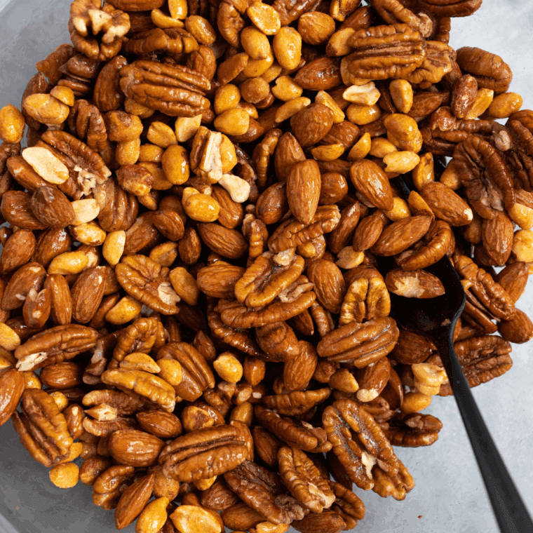 Mixing almonds, cashews, walnuts, pistachios, and pecans in a large bowl with optional honey, cinnamon, and salt.