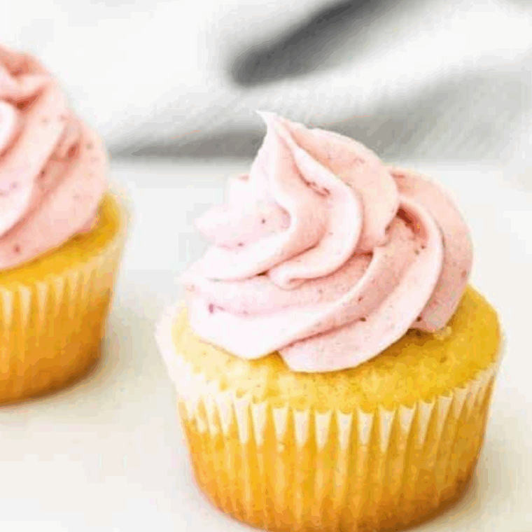 Creamy raspberry frosting swirled on a cupcake, made with fresh raspberries and jam.