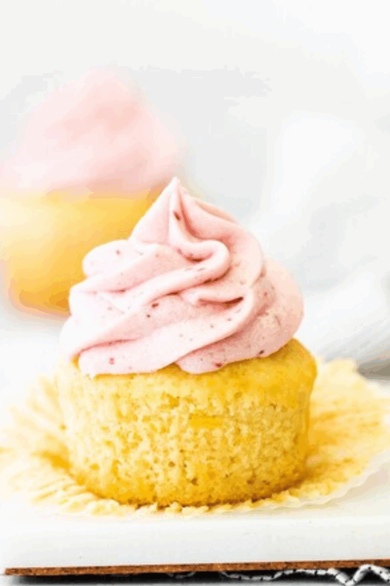 Close-up of creamy raspberry frosting with jam spread on a cupcake.