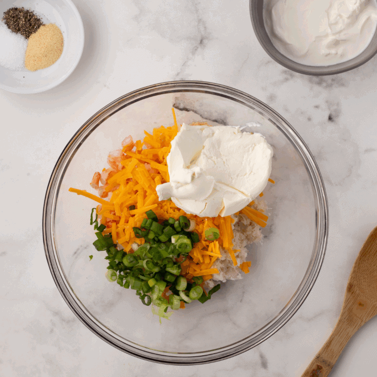 Baked potatoes halved with fluffy insides scooped out and mixed with butter, sour cream, cheese, and seasonings.