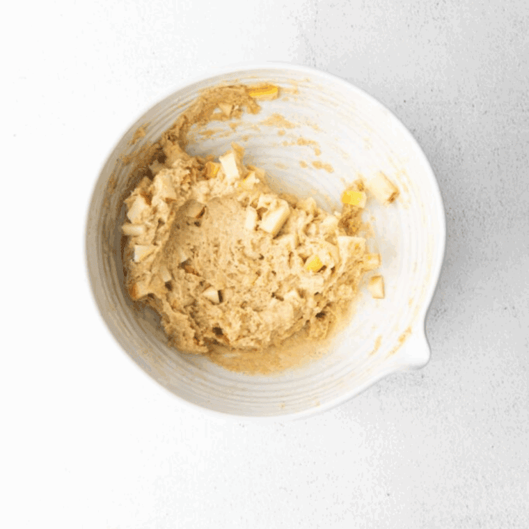 Folding spiced diced apples into thick and sticky sourdough fritter batter for even distribution