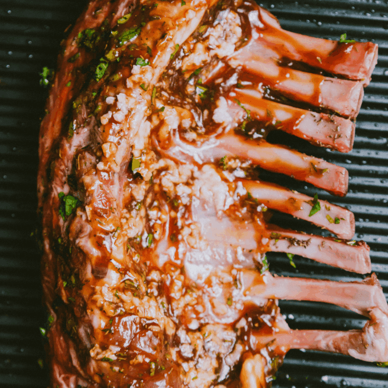 Lamb chops smoking on Traeger grill grates until medium-rare doneness