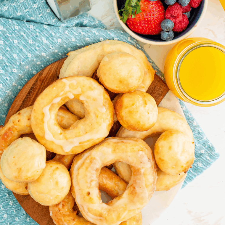 Air fryer Greek yogurt donuts topped with glaze and powdered sugar on a cooling rack.