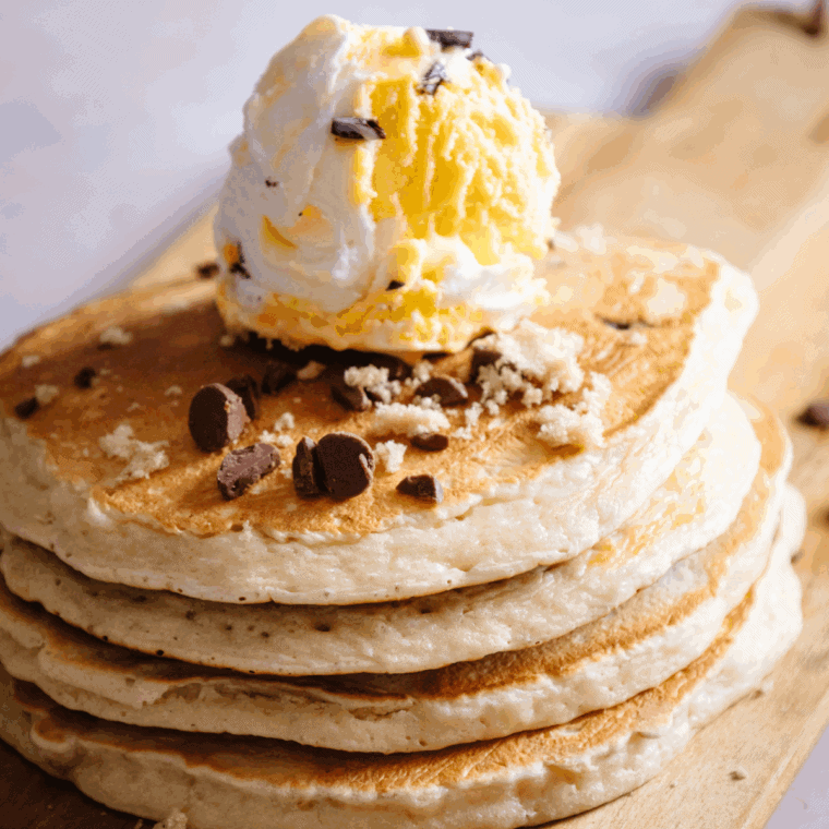 Stack of fluffy banana chocolate chip air fryer pancakes topped with syrup and extra chocolate chips on a breakfast plate.