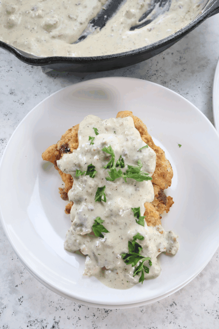 Homemade Bob Evans Country-Fried Steak with creamy white gravy on plate.