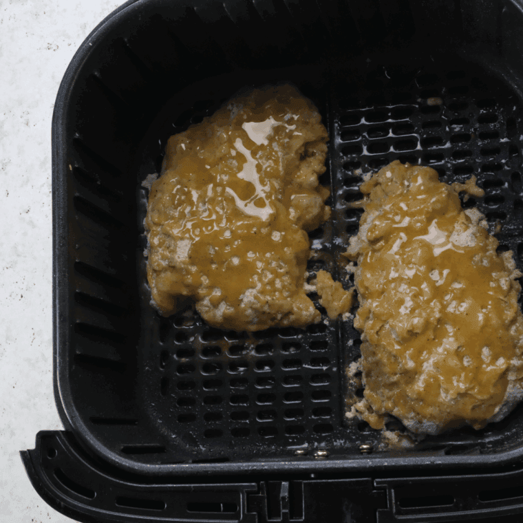 Golden brown, crispy air-fried steaks cooking in air fryer basket.
