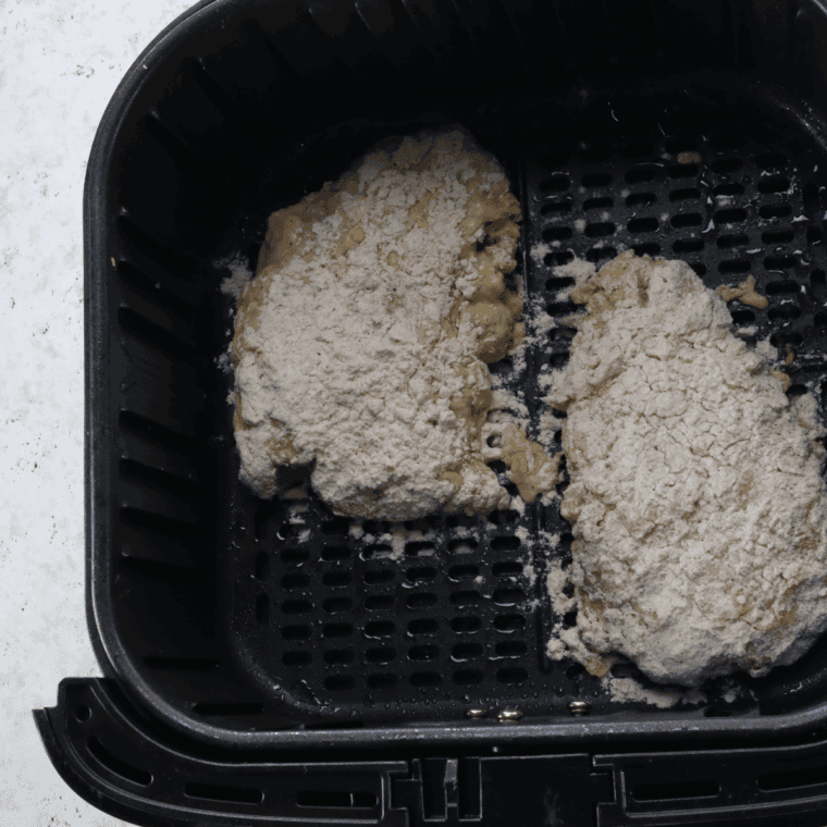Air fryer preheated to 400°F with breaded steaks in basket, ready to cook.